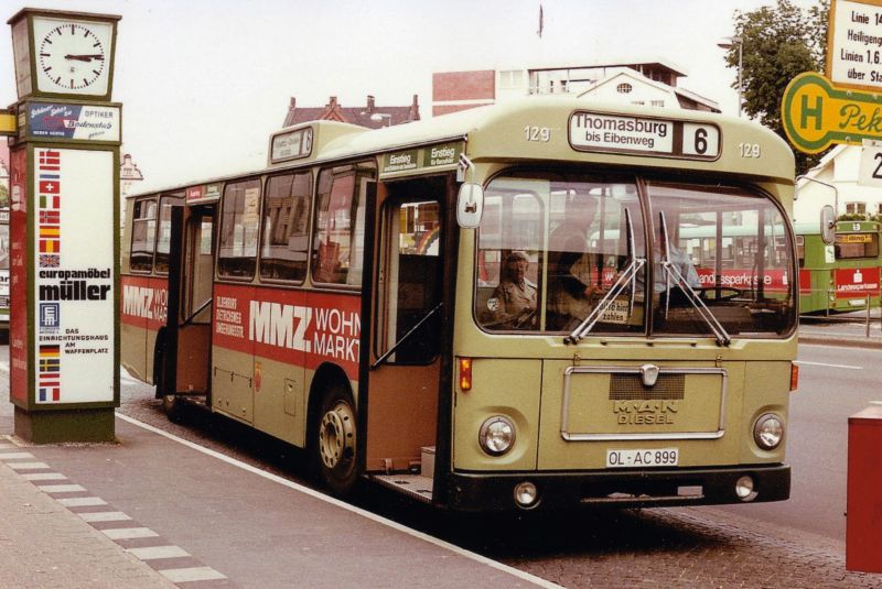 Wagen 129, OL-AC 899, EZ: 1973. Diese Aufnahme, die Werner Striepling im Juni 1978 machte, ist in mehrfacher Hinsicht betrachtenswert. Sie zeigt nicht nur Wagen 129 mit seiner ersten Werbung für MMZ-WOHNMARKT, sondern ist auch eine der wenigen Farbaufnahmen, wenn nicht die einzige bis jetzt, die einen Bus der  Dortmunder Serie  mit offenen Türen zeigt. Damit können wir einen kleinen Blick auf die Innenfarbe erhaschen. In den Bussen der OVB Pekol war der Innenraum in hellen und dunklen Grautönen gehalten. Hier ist deutlich eine bronzefarbene Lackierung der Türen zu erkennen. Auch die roten Haltestangen, die hier leider nicht zu sehen sind, hoben sich deutlich in den Bussen ab, zumal Pekol die Busse mit zusätzlichen Stangen ausstattete, die natürlich wieder die eigene Farbe hatten. Im Hintergrund rechts ist einer der ersten MAN SL 200 zu sehen. Das der Bus auf der Linie 5 eingesetzt ist, legt die Vermutung nahe, dass es sich um einen der Busse handelt, die einen Spätdienst bedienten. Wenden wir uns dem linken Bildrand zu. Leider fast vollständig durch die noch recht neue Werbeeinrichtung verdeckt, steht hier ein S 130 S. Der aufmerksame Besucher wird feststellen, dass ich bisher hier einen Setra mit weißer Frontwerbung nicht gezeigt habe. Es handelt sich um Wagen 16 mit seiner ersten Version der JUNO-Werbung. An der Front und an einer Seite war zudem Werbung für CARL-WILH. MEYER. Und zuletzt zu dem bereits angesprochenen Werbeträger. Diese Weiterentwicklungen der klassischen Litfaßsäule wurden, wenn ich mich richtig erinnere, Mitte der 70er Jahre an der zentralen Umsteigestelle aufgestellt. Nachts beleuchtet, zwangen sie die Fahrgäste den schönen breiten Bereich direkt am Bordstein zu verlassen und sich den Weg zu ihrem Anschlussbus zu bahnen. Meist unter Verwendung des Radweges, worauf der typische Oldenburger Radfahrer, natürlich ohne Licht unterwegs, in der Regel mit lautem Klingeln reagierte. Der versierte Zweiradprofi, der diese Strecke regelmäßig fuhr, wich dann in der Regel sofort auf den Fußweg aus und warf dabei gleich mal einen Blick in die Schaufenster von Hertie. Oder man quetschte sich als Fahrgast zwischen Säule und Bus hindurch, wenn man denn überhaupt vernünftig aussteigen konnte, denn je nachdem wie die Busse hielten, standen sie manchmal mit der hinteren Tür, so wie hier zu sehen, direkt vor so einem Hindernis. Für uns hat diese spezielle Säule allerdings noch einen Dienst parat. In ihr prangt ein Plakat für das EUROPAMÖBELHAUS MÜLLER. Somit bekommen wir einen leichten Eindruck des Aussehens von Wagen 165. Der trug diese Werbung nach seiner Indienststellung 1972. Neben Wagen 129 trug auch Wagen 130 zunächst die auf dem Bild gezeigte Werbung für MMZ-WOHNMARKT. Und wer weis, vielleicht bekommen wir ja an dieser Stelle auch noch mehr von Wagen 16 zu sehen, mal abwarten ...